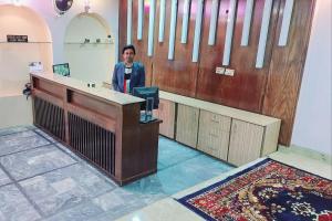 a man standing at a counter in a room at Hotel Shaheen Continental Multan in Multan