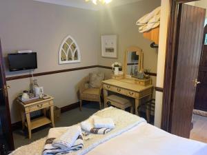 a bedroom with a bed and a desk and a mirror at Burnt Mill Cottage in Burnham on Crouch