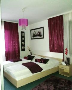 a bedroom with a large bed with purple curtains at Hotel Restaurant Toscana in Bad Orb