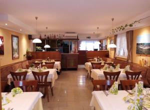 um restaurante com mesas brancas e cadeiras de madeira em Hotel Restaurant Toscana em Bad Orb