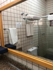 uma casa de banho com um espelho, um WC e toalhas em FLAT ILHA FLAT HOTEL em Ilhabela