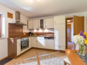 kuchnia z białymi szafkami i stołem z wazonem z kwiatami w obiekcie Appartement Salvenblick w mieście Hopfgarten im Brixental +7 zdjęć