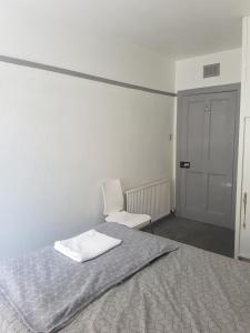 a bedroom with a bed and a white chair at Cosy Room in Galashiels in Galashiels