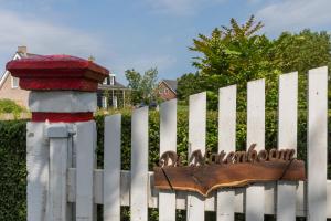 a white picket fence with a red fire hydrant at De Notenboom in Meliskerke