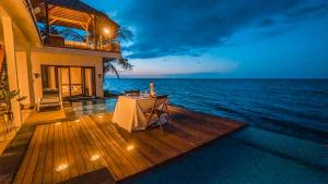 a table on the deck of a house overlooking the ocean at Air Sanih Beach Villa in Kubutambahan