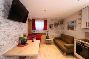 uma sala de estar com um sofá e uma televisão numa parede de pedra em Landhaus Gaspar em Wagrain