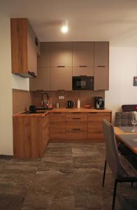 uma cozinha com armários de madeira e uma mesa num quarto em Shellter Apartament Nadmorski em Rogowo