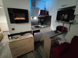 Una pequeña cocina con una estufa y un televisor en la pared. en Bienvenue chez nous, en Arc 2000