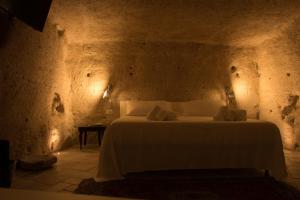 a bedroom with a white bed in a stone wall at LA DIMORA DELLE 3 ZIE in Matera