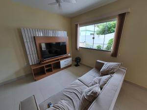 uma sala de estar com um sofá e uma televisão em Casa Duplex Iriri - Banheira e Piscina em Iriri