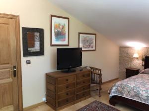 Un dormitorio con una cama y un televisor sobre una cómoda. en Villa Casa de Campo Los Carballos, en Tomiño