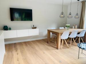 a dining room with a wooden table and white chairs at Haigis Lodge in Annaberg im Lammertal