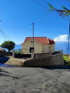 a white house with a red roof on a street at Casa AIDA SEA VIEW in Relógio do Poiso