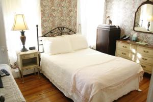 a bedroom with a bed and a dresser and a mirror at The Coolidge Corner Guest House: A Brookline Bed and Breakfast in Brookline