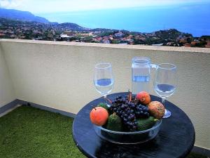 a bowl of fruit on a table with wine glasses at Casa AIDA SEA VIEW in Relógio do Poiso