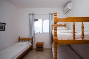 a bedroom with two bunk beds and a window at Pousada Canto das Pedras in Bombinhas