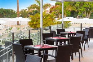 a row of tables and chairs on a balcony with umbrellas at Olé Tropical Tenerife Adults Only in Playa de las Americas