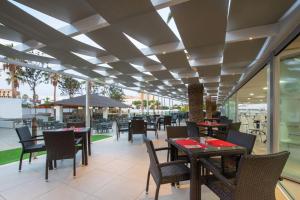 a restaurant with tables and chairs and windows at Olé Tropical Tenerife Adults Only in Playa de las Americas