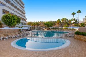 a swimming pool with chairs and umbrellas in a resort at Olé Tropical Tenerife Adults Only in Playa de las Americas