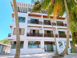 a white building with palm trees in front of it at The Pearl Seaview in Fulidhoo