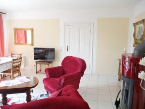 ein Wohnzimmer mit einem roten Stuhl und einem Sofa in der Unterkunft Ferienzimmer Weltenbummler,Rheinsberg in Rheinsberg