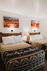 duas camas num quarto de hotel com pinturas na parede em Bryce Pioneer Village em Tropic