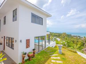 a white house with a view of the ocean at Villas Reef View Garden in Koh Samui