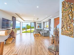 a living room with a couch and a television at Villas Reef View Garden in Koh Samui