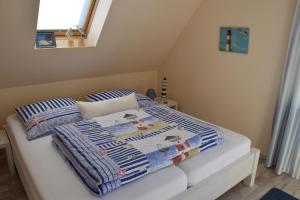 a bed with blue and white blankets and a window at "Ostseefische" in Gutglück
