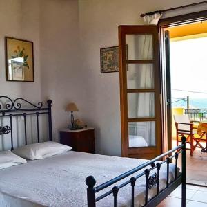 1 dormitorio con 1 cama y puerta a un balcón en Alexandraki Rooms, en Poulithra