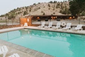 a swimming pool with white chairs and a building at Bryce Pioneer Village in Tropic