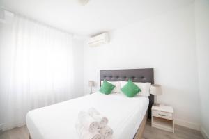 a bedroom with a white bed with green pillows at Apartment IFEMA-Airport in Madrid