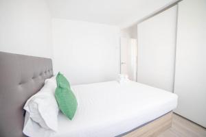- une chambre avec un lit blanc et un oreiller vert dans l'établissement Apartment IFEMA-Airport, à Madrid