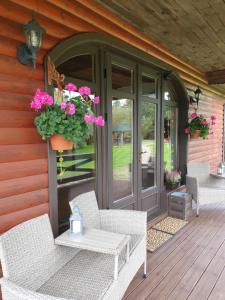 un porche con sillas de mimbre y flores en una casa en Brīvdienu māja Amatnieki, en Kuldīga