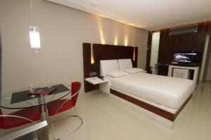 a bedroom with a bed and a table and a television at Raru's Motel Cidade Jardim (Adult Only) in Natal