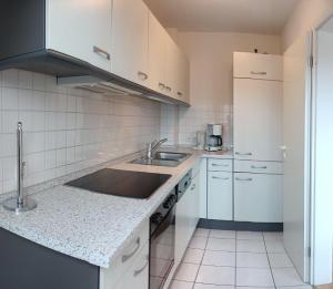 a kitchen with white cabinets and a sink at BUPA02208-Ferienwohnung-Passat in Burg auf Fehmarn