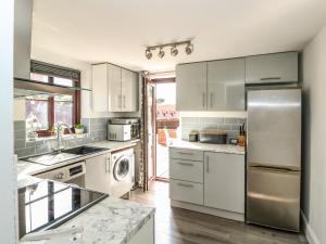 a kitchen with white cabinets and a stainless steel refrigerator at Chalk Cottage in Thetford