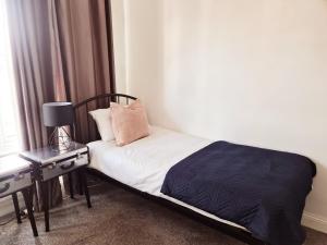 a bedroom with a bed and a night stand with a lamp at Berrygate in Ipswich