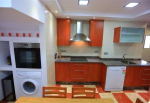 cocina con armarios de madera, lavadora y secadora en Casa Montes Del Castillo, en Almuñécar