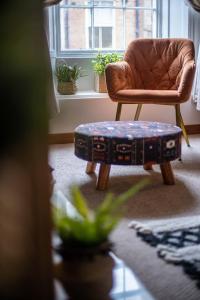 sala de estar con silla marrón y taburete en The Bottles Lodge, en Alnwick