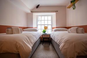 two beds in a room with a window at The Bottles Lodge in Alnwick