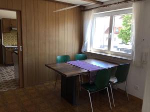 Cette chambre comprend une table en bois et des chaises vertes. dans l'établissement OG Villingendorf, à Villingendorf