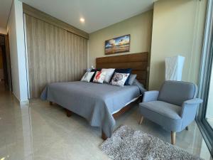 a bedroom with a bed and a chair at Camino al Mar exclusivo Departamento acceso directo playa in Mazatlán +55 photos