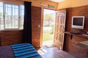 um quarto com uma porta e uma televisão e uma porta com uma janela em Posada Tinktinkie em Santa Rosa de Calamuchita