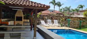 a pool with chairs and a pavilion next to a house at Casa de Temporada in Juquei