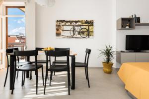 Civico40 Luminoso appartamento con balconi e garage privato في فيرونا: غرفة طعام مع كراسي سوداء وتلفزيون