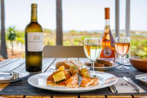 a table with a plate of food and two bottles of wine at AP Cabanas Beach & Nature - Adults Friendly in Cabanas de Tavira