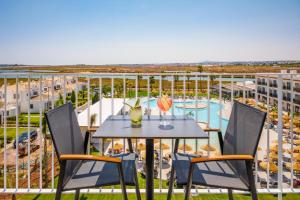 a balcony with a table and chairs and a pool at AP Cabanas Beach & Nature - Adults Friendly in Cabanas de Tavira