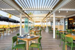 a restaurant with wooden tables and green chairs at AP Cabanas Beach & Nature - Adults Friendly in Cabanas de Tavira