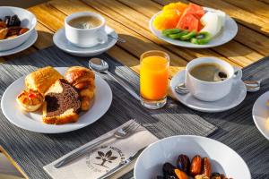 a table with plates of breakfast foods and cups of coffee at AP Cabanas Beach & Nature - Adults Friendly in Cabanas de Tavira